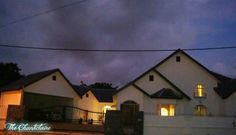 a white house sitting on the side of a road at night with clouds in the sky