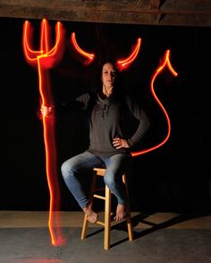 a woman is sitting on a stool with red lights in the shape of devil's horns