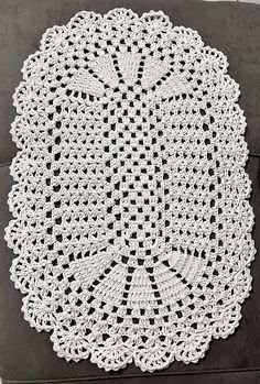 a white crocheted doily sitting on top of a black couch next to a pillow