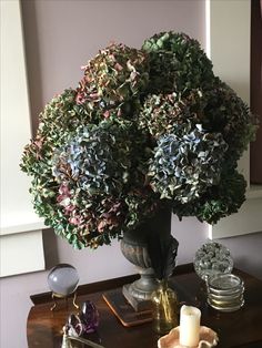 a vase filled with lots of purple flowers on top of a table next to candles