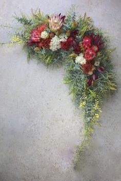 an arrangement of flowers and greenery arranged in the shape of a heart on a concrete surface