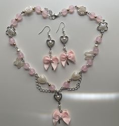 A pink pearlescent necklace with pink glass beads, and white pearls with a bow pendant for necklace and earring. Collares Coquette, Coquette Necklace, Coquette Jewelry, Pink Coquette, Bow Necklace, Jewelry Accessories Ideas, Pink Jewelry, Bow Earrings, Fancy Jewelry