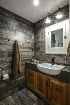 a bathroom with wooden walls and flooring, two lights on the wall above the sink