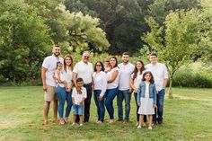 a large family poses for a photo in the grass with trees in the back ground