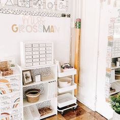 a room filled with lots of white boxes and shelves next to a wall covered in pictures