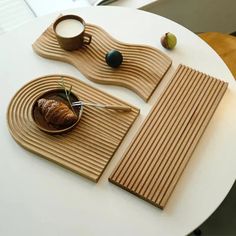 a white table topped with two wooden trays filled with pastries and coffee cups