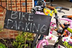 a sign that says bike parking is posted on the front of a pink and green bicycle