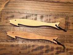 two wooden knives sitting on top of a wooden table next to each other with black handles