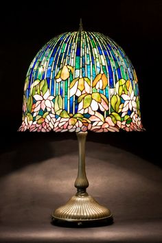 a stained glass lamp on a table with a black background and shadow from the light