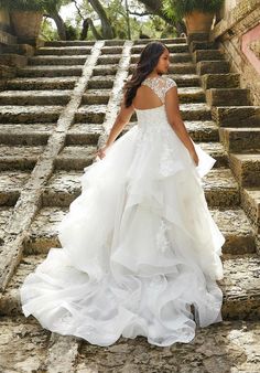 a woman in a wedding dress walking up some steps with her back to the camera