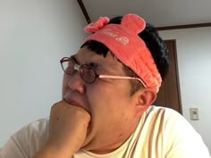 a man with glasses and a pink hat on his head is looking at the camera