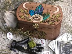 a wooden box sitting on top of a white rug next to cards and flowers in black gloves