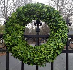 a wreath is hanging on a fence in front of some trees