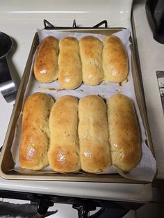 six loaves of bread sitting on top of a baking pan next to an oven