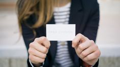 a woman holding up a business card that says open studios