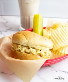 a sandwich and chips on a plate next to a glass of milk