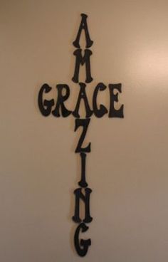 a metal cross with the word grace hanging from it's side on a wall