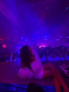 a woman sitting on top of a table in front of a crowd at a concert