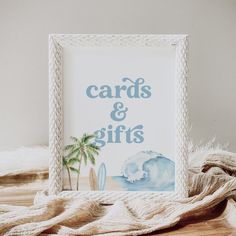 a card and gift box sitting on top of a wooden table next to a blanket