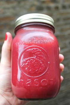 a person holding a red mason jar in their hand