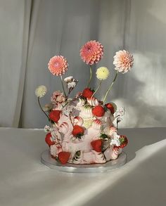 a cake decorated with flowers and strawberries on a table