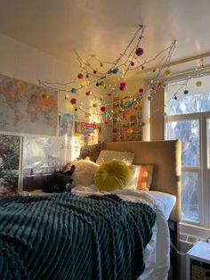 a cat is sitting on the edge of a bed in a room with lights strung from the ceiling