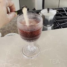 a person pours wine into a glass on a kitchen counter with an oven in the background