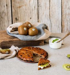 some food is laying out on a table next to a bagel and two kiwis