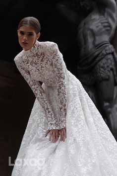 a woman in a white wedding dress standing next to a statue with her hands on her hips