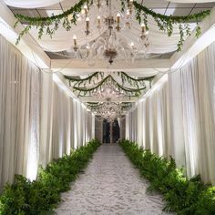 an indoor wedding venue decorated with greenery and chandelier hanging from the ceiling