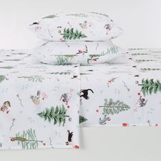 the bedding is decorated with christmas themed animals and pine trees on white linens