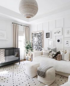 a living room with white furniture and black and white decor on the walls, along with a baby's crib