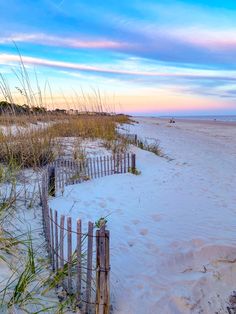 the beach is covered in white sand and sea oats as the sun goes down