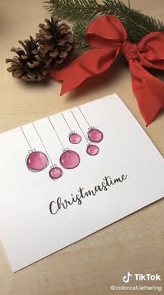 a christmas card with three ornaments hanging from it