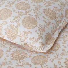 a close up of a bed with a white and gold floral pattern on the sheets