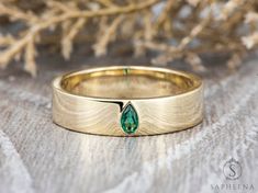 a close up of a gold ring with a green stone