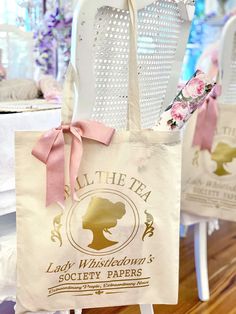 two white chairs with pink bows on them and some tea bags hanging from the back