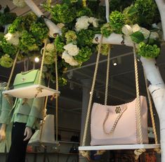 a woman's handbag and purse are on display in a store with flowers hanging from the ceiling