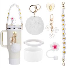 the contents of a white purse and keychain, including a coffee cup with pom - poms