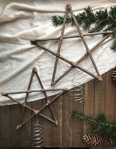 a star made out of sticks and some pine cones on top of a wooden table