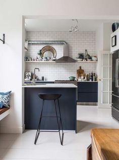 a kitchen with an island and bar stools in it, along with white tile walls