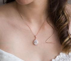 a woman wearing a necklace with a diamond on it