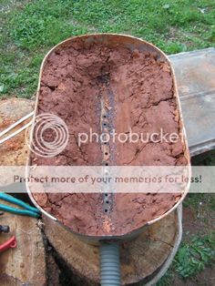 a metal tub filled with dirt next to a pile of wood