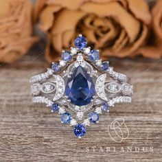 a blue and white diamond ring on top of a wooden table with roses in the background