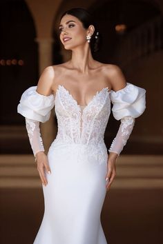 a woman in a white wedding dress posing for the camera with her hands on her hips