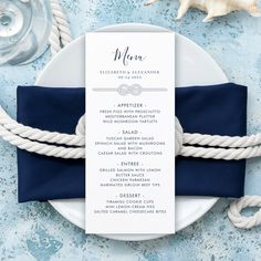 a table setting with blue and white napkins, silverware and seashells