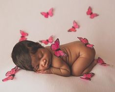 a baby is sleeping with pink butterflies flying around