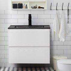 a white bathroom with black and white tile on the floor, shelves above the sink