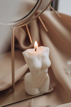 a white candle sitting on top of a table next to a mirror