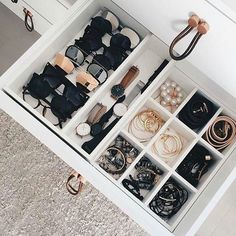 an open drawer filled with lots of glasses and other items on top of carpeted floor